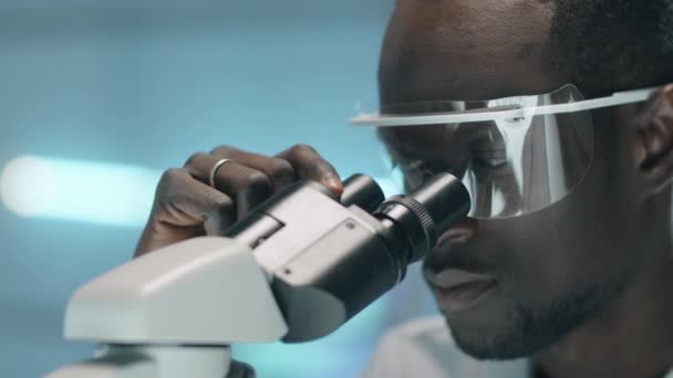 Κοντινό Πλάνο Του Νεαρού Αφροαμερικανού Επιστήμονα Προστατευτικά Γυαλιά Που Κοιτάζει — Αρχείο Βίντεο