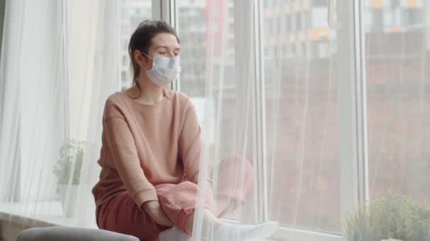 Pensive Brunetka Žena Lékařské Tváři Maska Sedí Parapetu Dívá Oknem — Stock video