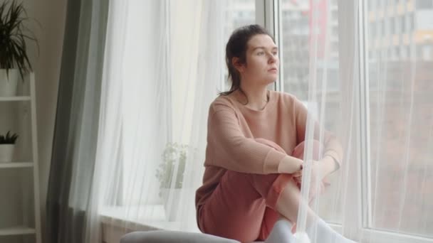 Betrachtet Eine Junge Frau Bequemer Hauskleidung Die Auf Einem Fensterbrett — Stockvideo