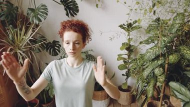 Genç kızıl saçlı bir kadının el pençe divan durup göğsünün önünde durduğu ve yoga yaparken başını çevirdiği belden yukarı pozlar.