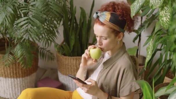 Młoda Ładna Kobieta Czerwonymi Kręconymi Włosami Pisząca Smartfonie Jedząca Zielone — Wideo stockowe