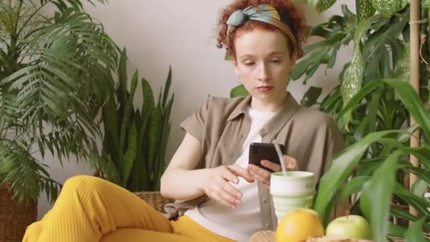 Genç Kızıl Saçlı Kadın Internette Akıllı Telefondan Sörf Yapıyor Evde — Stok video
