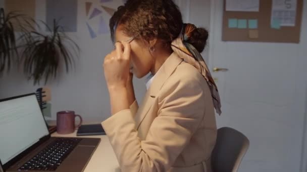 360度のトラッキングショットの疲れアフリカ系アメリカ人ビジネスマンの女性は 眼鏡を取り 鼻のブリッジをこすり その後 オフィスで過労しながらノートパソコンに入力します — ストック動画