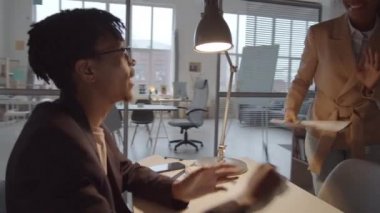 360 derece Afrika kökenli Amerikalı erkek yöneticinin masa başında çalışırken çekimleri. Çalışma saatlerinde iş arkadaşlarıyla iş projelerini kontrol edip tartışıyorlar.