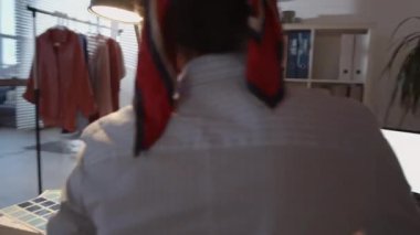 360 derecelik çekimde Afrikalı Amerikalı kadın tasarımcı stüdyoda oturuyor ve renkli keçeli kalemlerle moda çizimleri yapıyor.