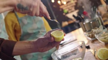 Hollanda açısı, aşçılık kursu sırasında çatal kullanan ve cam kaseye limon suyu sıkan erkek aşçının yakın plan çekimi.