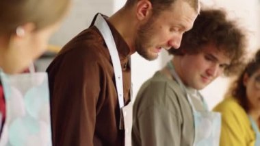 Erkek aşçı limon gösteriyor ve genç neşeli öğrencilere yemek pişirme ustası dersi verirken bir şeyler anlatıyor.