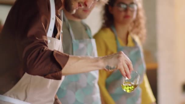 Kippschuss Von Männlichen Koch Gießt Auf Pfanne Während Kochkurs Gibt — Stockvideo