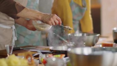 Önlüklü erkek aşçının kızartma tavasına rendelenmiş peynir ekleyip yüksek lisans yaparken çok ırklı erkek ve kadın öğrencilerle konuştuğu sahneyi kaldır.