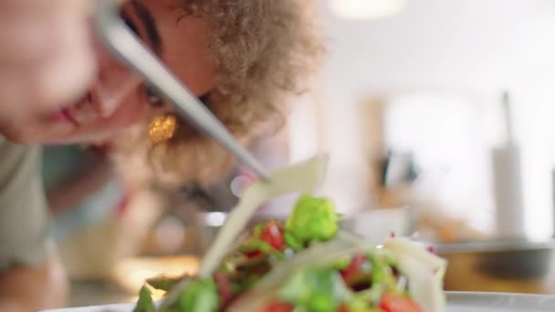 在盘子里放菜的时候 把一个年轻人用镊子把烤奶酪条放在沙拉上的特写镜头倾斜下来 — 图库视频影像
