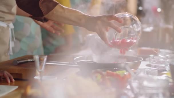 Uchwyć Profesjonalnego Kucharza Wkładającego Kawałki Pomidorów Patelni Rozmawiającego Wielonarodowymi Uczniami — Wideo stockowe