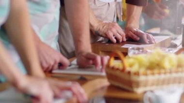 Aşçılık kursunda birlikte yemek pişirirken sarımsak karanfillerini bıçakla ezen bir grup öğrenci ve erkek aşçı.