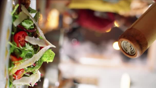 将调料加入色拉与木制胡椒磨盘一起食用的垂直特写镜头 — 图库视频影像