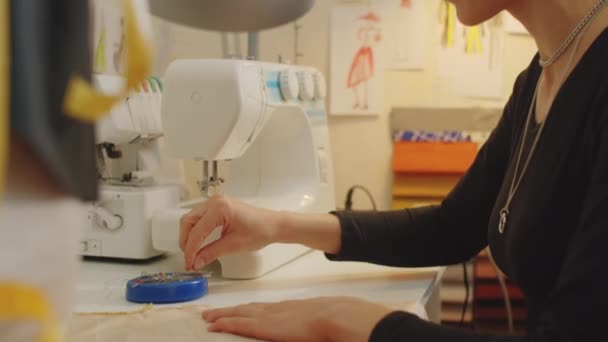 テーラースタジオで作業しながら 生地に縫製ピンを添付若い女性のドレスメーカーのショットを傾けます — ストック動画