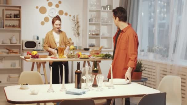 Vrolijke Jonge Man Dekken Tafel Voor Diner Met Gasten Chatten — Stockvideo