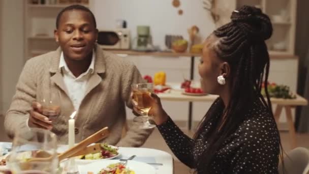美しい若いアフリカ系アメリカ人の女性がトーストを与えます 自宅でディナーパーティーを開催しながら 陽気で多様な友人とワインを飲みながら ガラスをクリック — ストック動画