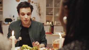 Beyaz bir adam yemek yiyor ve arkadaşlarıyla akşam yemeği partisinde Afrikalı Amerikalı bir kadınla sohbet ediyor.