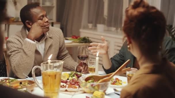 若いハンサムな男笑顔 トーストを与え 自宅のディナーパーティーで幸せな多民族の友人とワイングラスをクリック — ストック動画