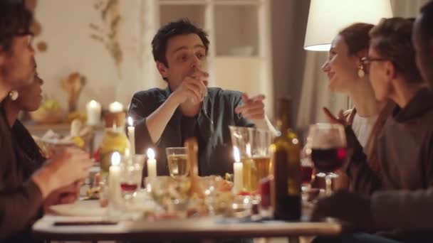若い幸せな多民族の男性と女性が一緒にトーストでワイングラスを笑いながら 家で夜の休日の夕食を持っている間 — ストック動画
