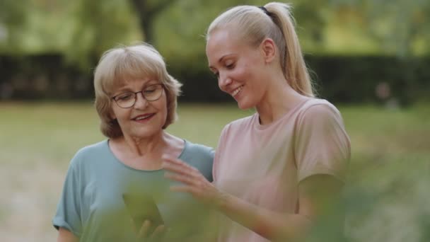 Portrait Elderly Woman Young Female Fitness Instructor Using Smartphone Talking — Stock Video