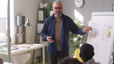 Üst düzey iş adamı ofisteki şirket toplantısında çok ırklı meslektaşlarına gündelik kıyafet tanıtımı yapıyor.