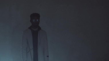Genç Afro-Amerikalı adam karanlık bir odada duruyor. Üzerinde hareket eden düz bir lazer ışığı var.