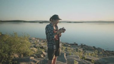 Genç bayan fotoğrafçının günbatımında profesyonel kamerayla güzel gölün fotoğraflarını çektiği orta boy bir fotoğraf.