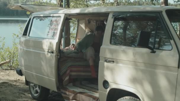 暑假时 年轻女子坐在旅游拖车里 在湖边露营 爱抚可爱的金毛猎犬 — 图库视频影像
