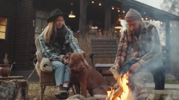 Man Putting Firewood Burning Bonfire Sitting Next His Wife She — Stock Video