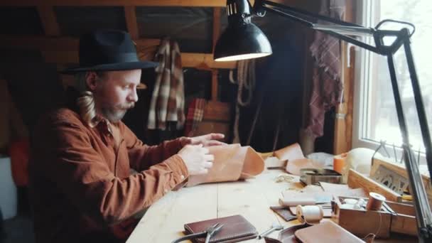 Blanke Ambachtsman Zittend Aan Het Bureau Snijdend Stuk Leer Tijdens — Stockvideo