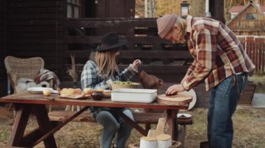 Adam ızgara et kesip tabakta servis ederken karısı da arka bahçede köpek maması veriyor.
