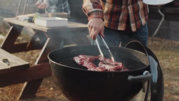 Sakallı Adamın Karımla Dışarıda Bbq Pişirirken Bifteğini Diliyle Izgaraya Koyduğu — Stok video