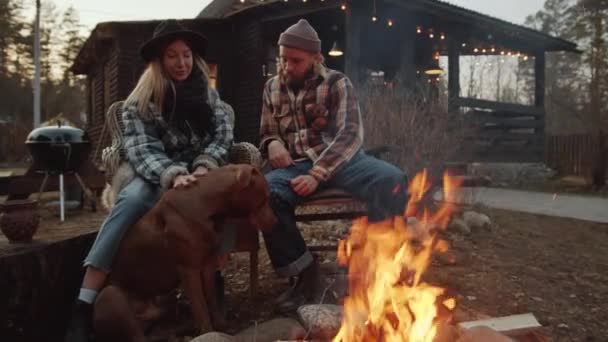 Young Caucasian Couple Sitting Bonfire Evening Petting Cute Dog While — Stock Video