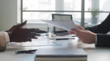 Çok ırklı iki erkek iş ortağının anlaşma imzalarken ve ofis masasında el sıkışırken yakın çekim.