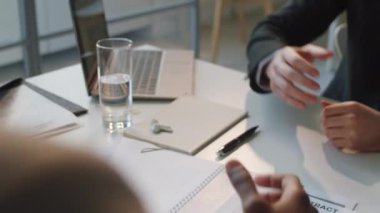 İki çok ırklı iş adamının ofis masasında yan yana otururken el sıkışmalarına yakından bakın.