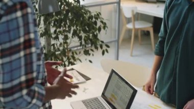 Tanımlanamayan, çok ırklı erkek iş arkadaşlarının ofis masasında otururken el sıkışarak birbirlerini selamladıkları yüksek açılı bir çekim.