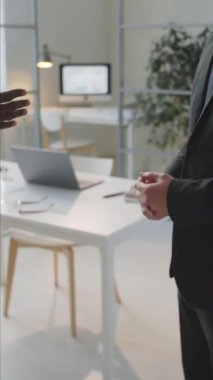 Ofiste duran iki etnik çeşitlilikte iş adamının el sıkışmasının dikey yakın çekimi