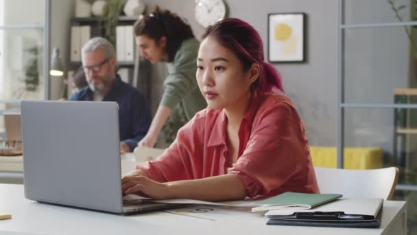 Молодая Азиатка Стажер Розовыми Волосами Работает Ноутбуке Офисе — стоковое видео