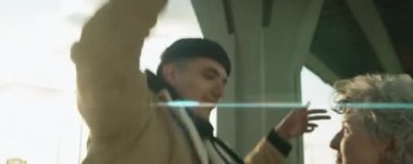 Anamorfik kamera görüntüsü, genç pozitif erkek ve kadının birbirine baktığı ve şehir köprüsünün altında sokak dansı yaptığı.