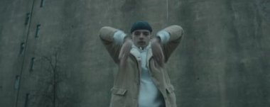 Genç çiftin eski beton binaya karşı açık havada kamera önünde vogue dansı yaptığı anamorfik bir çekim.