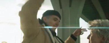 Anamorfik kamera görüntüsü, genç pozitif erkek ve kadının birbirine baktığı ve şehir köprüsünün altında sokak dansı yaptığı.