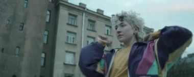 360 derece anamorfik çekim. Sarışın, klasik bombacı ceketli genç bir bayan dansçı. Şehir dışında kameraya bakıp dans ediyor.