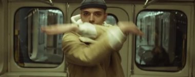 Anamorfik çekimde, genç profesyonel erkek dansçı moda dans ediyor ve metro treninde kameraya yaklaşıyor.