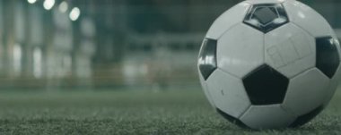 Kapalı alanda futbol topunu tekmeleyen tanınmayan bir futbolcunun anamorfik görüntüsünü kapatın.