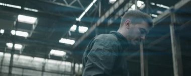 Profesyonel futbol atletinin top hokkabazlığı ve terk edilmiş bir binada boynunun arkasında dengeleme anamorfik çekimi.