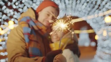 Arka planda öpüşen romantik bir çiftin ışık tünelinde tuttuğu seçici odak fotoğrafını çek.