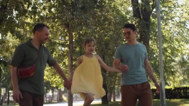 现代Lgbtq家庭的一个孩子手牵手在当地公园散步 拍摄了一个中等长度的慢镜头 — 图库视频影像