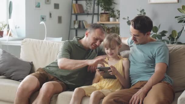 男女同性恋 双性恋 变性者和变性者家庭的一个小女儿在家里一起坐在沙发上上网 — 图库视频影像