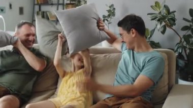 Mutlu eşcinsel çiftin, güzel kızlarıyla oturma odasında yastık kavgası yaparken orta yatay görüntüsü.