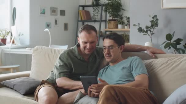 两个相恋的英俊白人男人坐在沙发上上网 坐在数字平板电脑上的肖像 — 图库视频影像